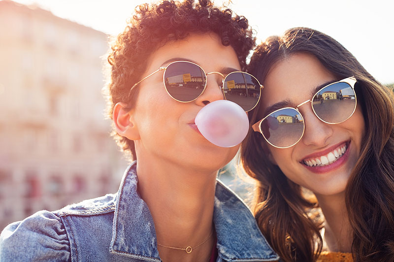 Two women chewing gum with good oral health habits