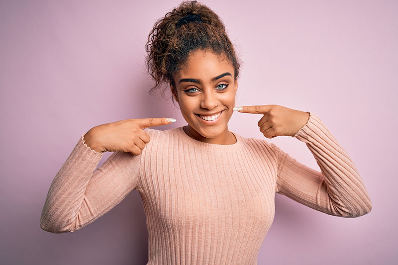 Young woman smiling and pointing at teeth